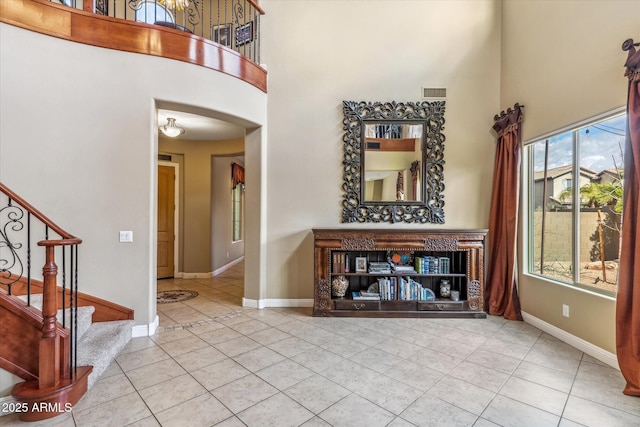 foyer entrance featuring stairway, visible vents, a towering ceiling, and baseboards