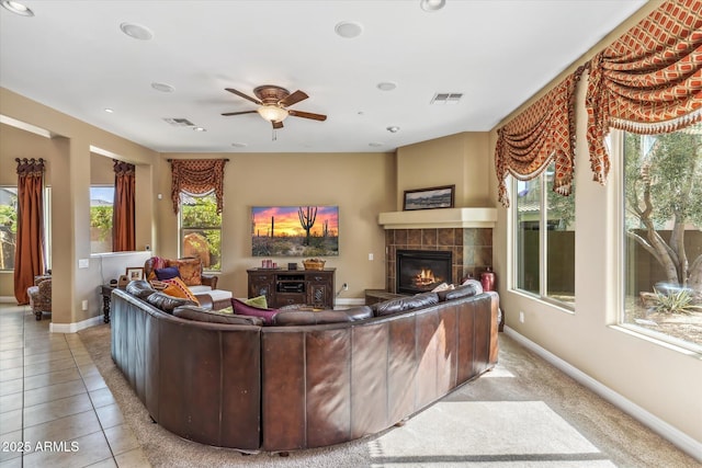 living area featuring baseboards, visible vents, a tiled fireplace, and tile patterned floors