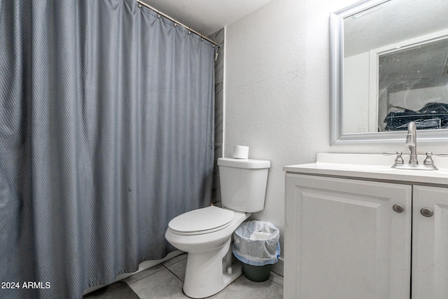 bathroom featuring vanity, a textured wall, tile patterned floors, and toilet