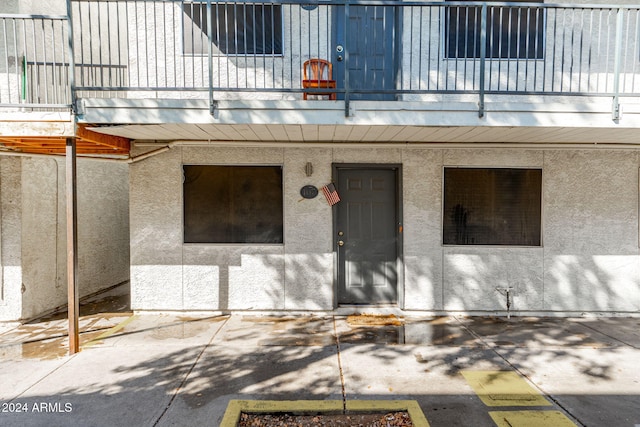 property entrance featuring stucco siding and a balcony