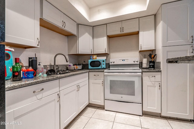 kitchen with light tile patterned flooring, white electric stove, a sink, and white cabinetry