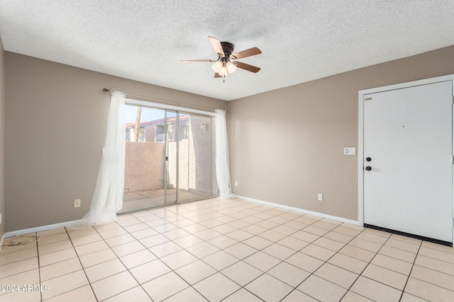 spare room featuring ceiling fan, light tile patterned floors, and a textured ceiling