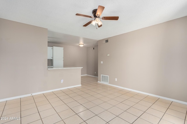 spare room with ceiling fan, a textured ceiling, and light tile patterned floors