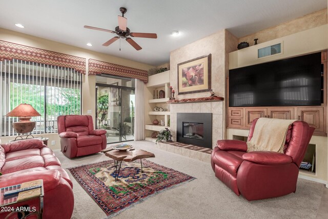 living room featuring ceiling fan, carpet floors, and a tiled fireplace