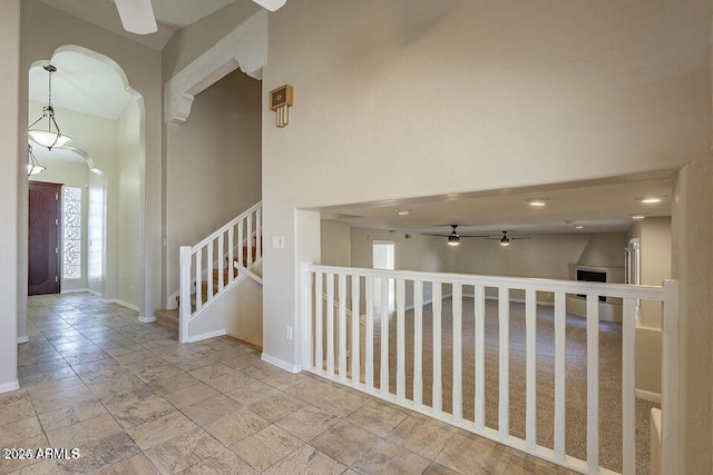 hallway featuring a high ceiling, stone tile floors, stairway, and baseboards