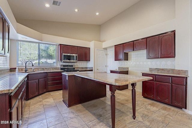 kitchen with reddish brown cabinets, light stone counters, stainless steel appliances, visible vents, and decorative backsplash