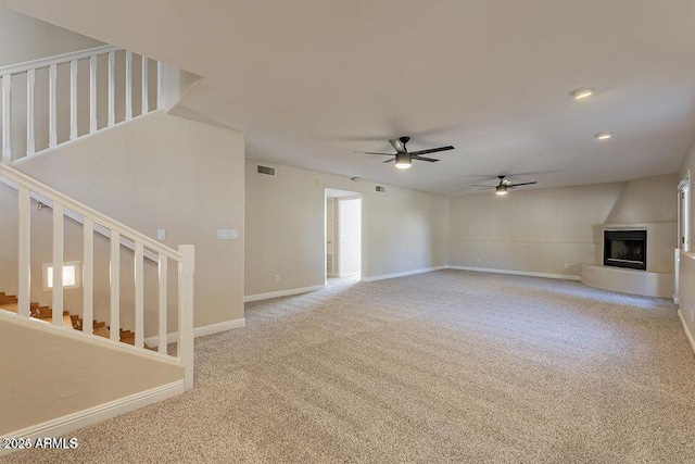 unfurnished living room featuring visible vents, a fireplace, carpet flooring, and stairs