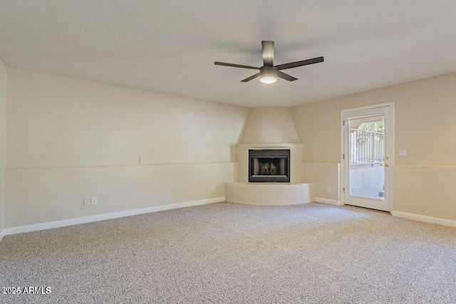 unfurnished living room with carpet floors, a large fireplace, ceiling fan, and baseboards