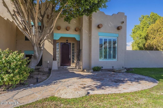 doorway to property featuring a yard and stucco siding