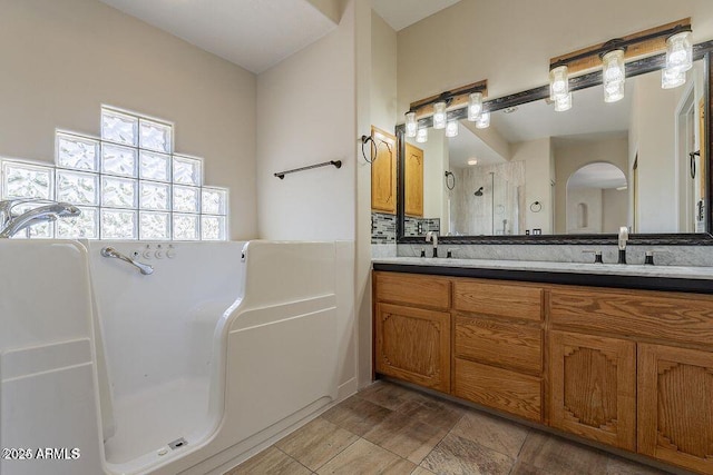 full bathroom featuring tasteful backsplash, a sink, a shower stall, and double vanity