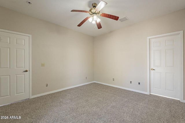 carpeted spare room with a ceiling fan, visible vents, and baseboards