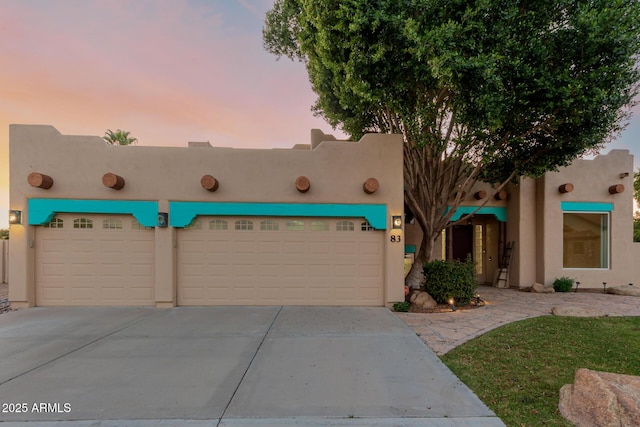 view of front of house with an attached garage, driveway, and stucco siding