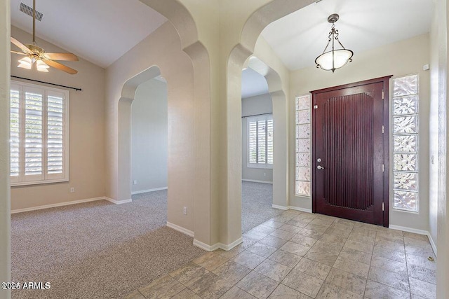 foyer with lofted ceiling, arched walkways, carpet flooring, visible vents, and baseboards