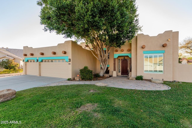 pueblo-style house with driveway, a front lawn, and stucco siding