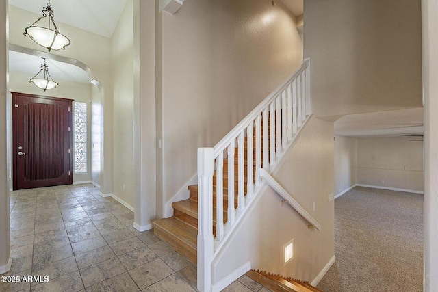 entryway with stairway, baseboards, arched walkways, and stone tile flooring