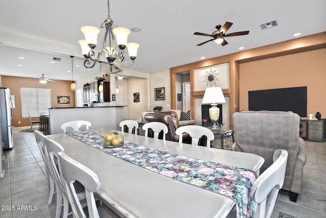 tiled dining room with ceiling fan with notable chandelier