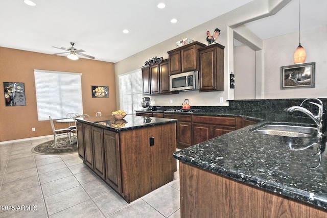 kitchen with ceiling fan, sink, a center island, hanging light fixtures, and dark brown cabinets