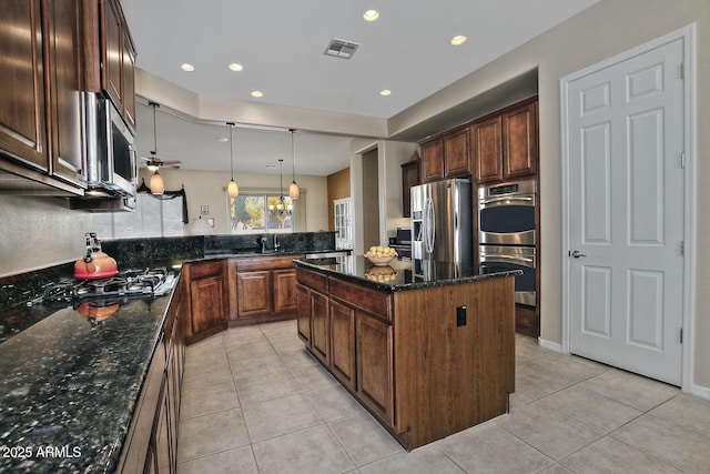 kitchen featuring a kitchen island, dark stone countertops, hanging light fixtures, and appliances with stainless steel finishes