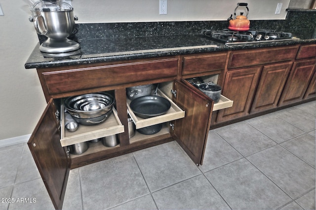 interior details featuring dark brown cabinets, dark stone counters, and gas cooktop