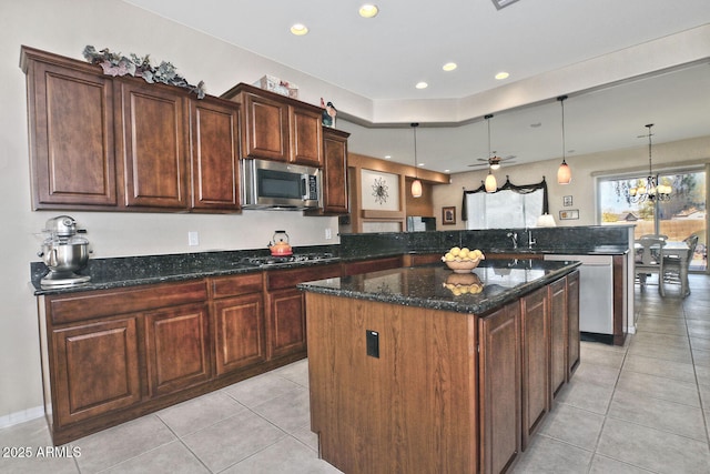 kitchen with a center island, hanging light fixtures, dark stone counters, ceiling fan with notable chandelier, and appliances with stainless steel finishes