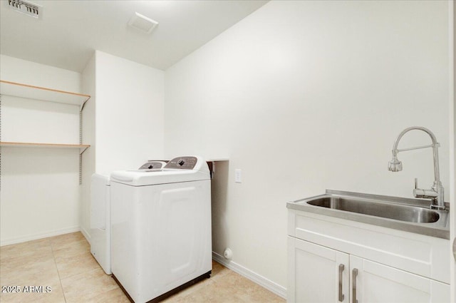 clothes washing area with washer and dryer, cabinets, light tile patterned floors, and sink