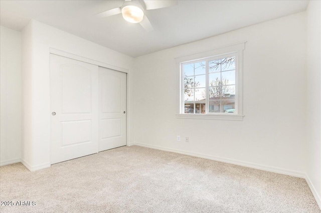 unfurnished bedroom with ceiling fan, light colored carpet, and a closet