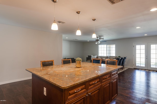 kitchen with pendant lighting, a breakfast bar, french doors, ceiling fan, and a kitchen island