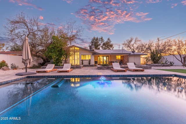 pool at dusk with a patio area