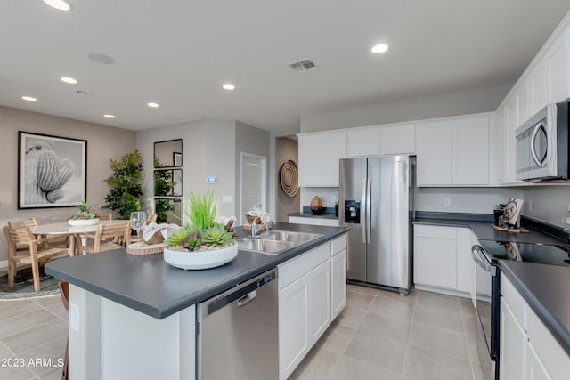 kitchen featuring white cabinetry, sink, a center island with sink, light tile patterned floors, and appliances with stainless steel finishes