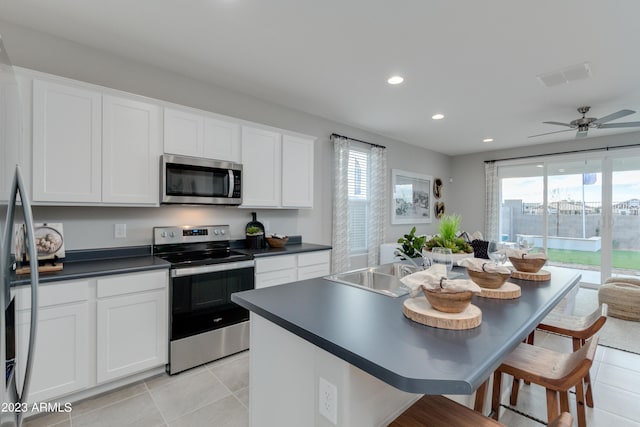 kitchen with a wealth of natural light, ceiling fan, white cabinetry, and appliances with stainless steel finishes