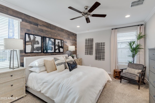 carpeted bedroom featuring ceiling fan, wood walls, ornamental molding, and multiple windows