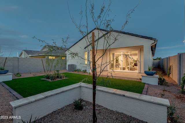 rear view of property featuring a lawn and central AC unit