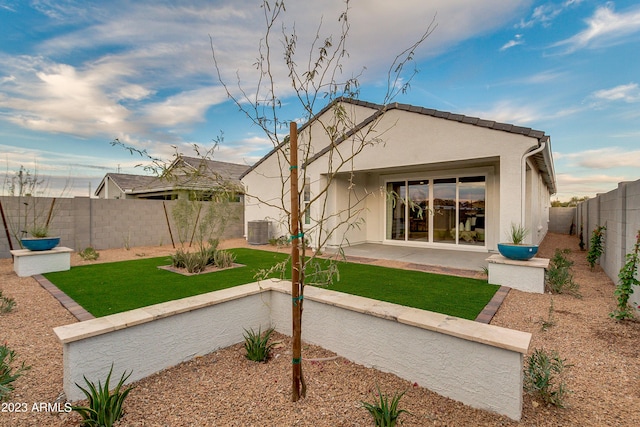 rear view of house featuring a lawn, cooling unit, and a patio area