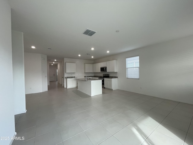 kitchen with light tile patterned flooring, a center island, white cabinets, and stainless steel appliances