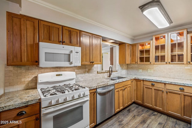 kitchen featuring crown molding, glass insert cabinets, brown cabinets, white appliances, and a sink