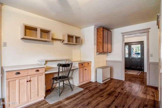 interior space with wainscoting, a textured ceiling, dark wood-style floors, and built in desk