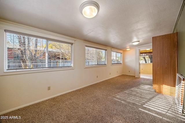 carpeted empty room with vaulted ceiling, baseboards, and a textured ceiling