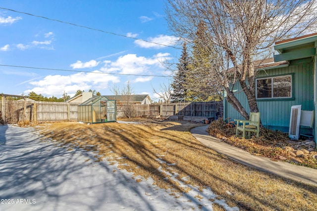 view of yard featuring a greenhouse, an outbuilding, and a fenced backyard