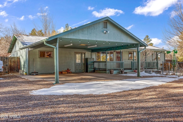 rear view of house featuring a carport, a porch, concrete driveway, and fence