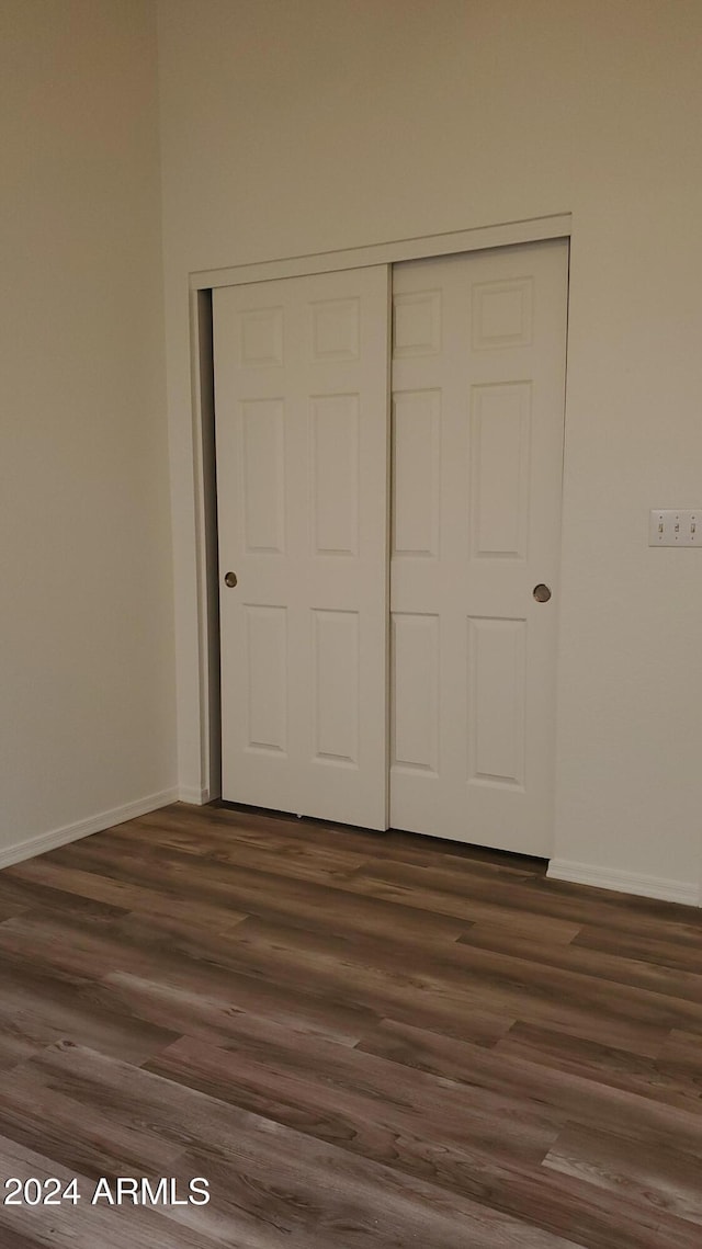 unfurnished bedroom with dark hardwood / wood-style flooring and a closet