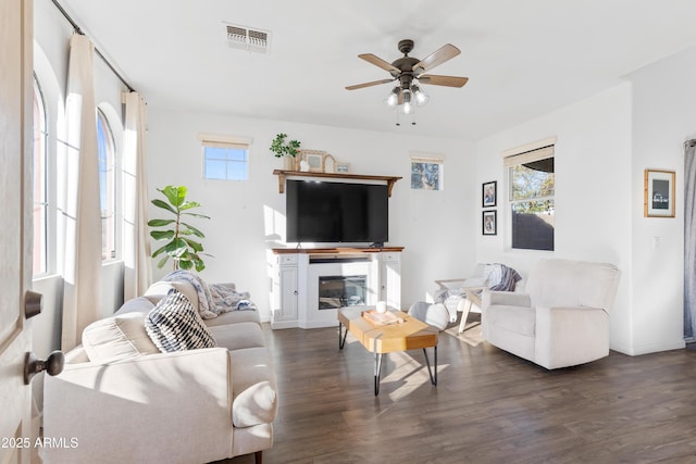 living room featuring visible vents, plenty of natural light, dark wood-type flooring, and ceiling fan