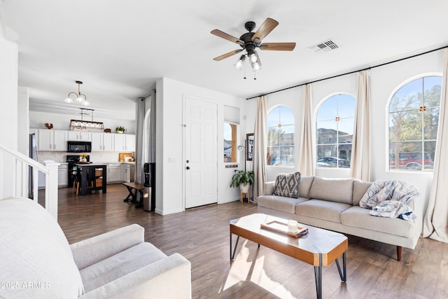 living room with visible vents, baseboards, ceiling fan, and dark wood-style flooring