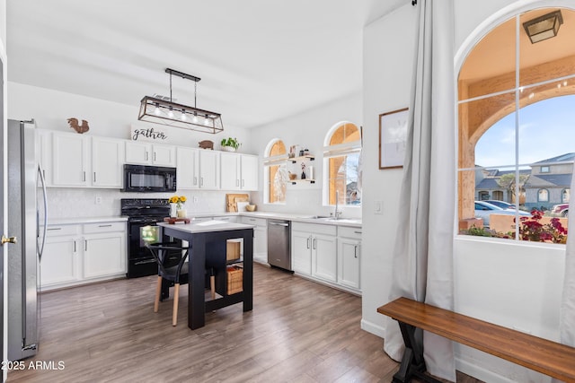 kitchen with plenty of natural light, backsplash, black appliances, and wood finished floors