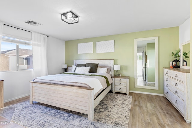 bedroom with light wood-style floors, visible vents, and baseboards