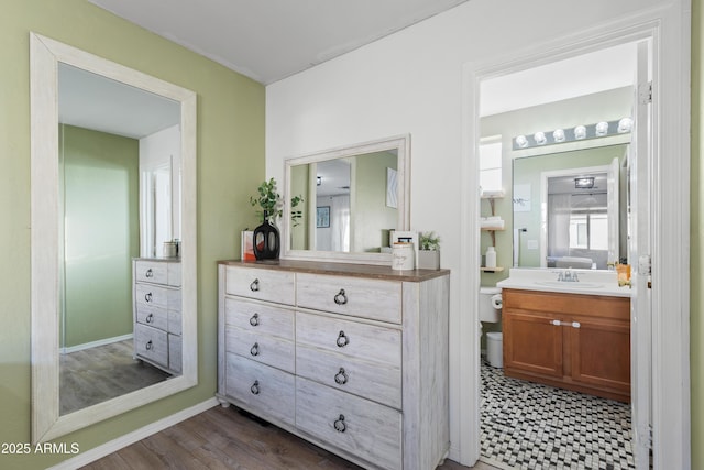 bathroom with toilet, vanity, and wood finished floors