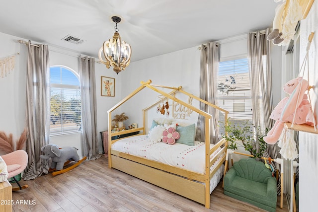 bedroom with visible vents, light wood-style floors, and a chandelier