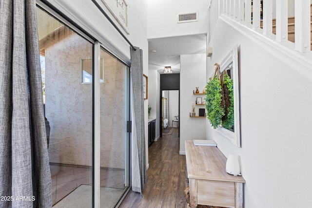 hall featuring dark wood finished floors, visible vents, and a healthy amount of sunlight