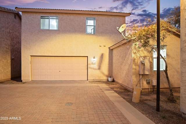 view of front of home featuring stucco siding, decorative driveway, and an attached garage