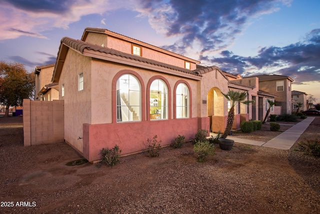 property exterior at dusk with stucco siding and a tiled roof