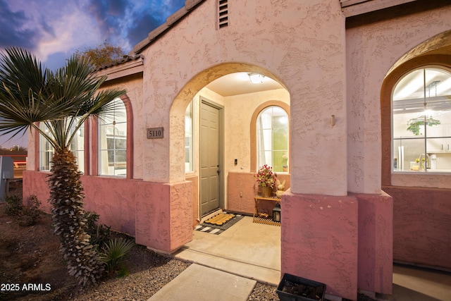 doorway to property featuring stucco siding